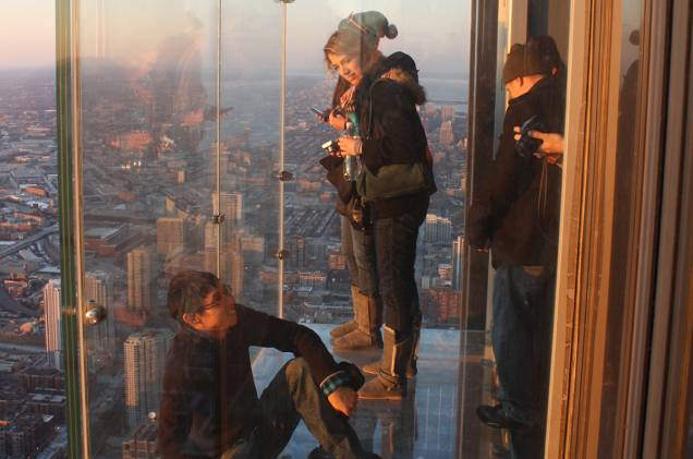 Segura a vertigem: uma gente corajosa espiando Chicago, lá dos cubos de vidro do mirante Skydeck Segura a vertigem: uma gente corajosa espiando Chicago, lá dos cubos de vidro do mirante Skydeck