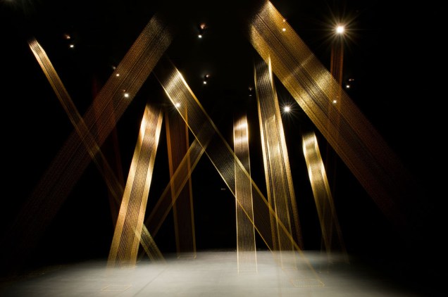 Fios dourados finos e iluminação especial criam um efeito diferente a cada ângulo na obra T-teia, de Lygia Pape.