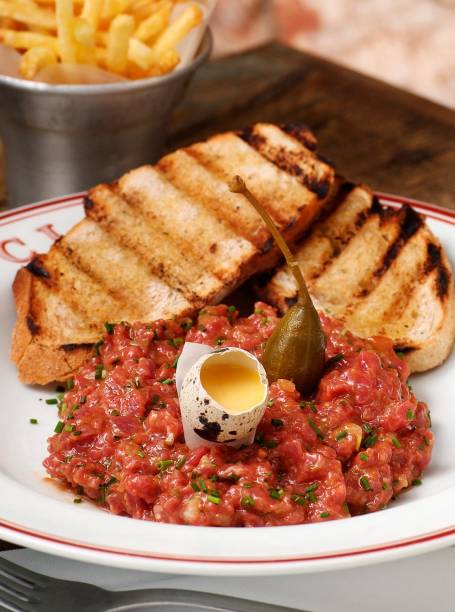 Tartare com ovo de codorna com a gema mole, batatas fritas, salada e torradas