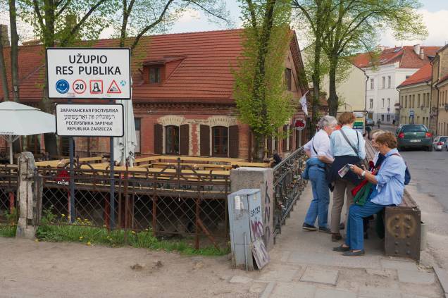 Turistas na entrada de Uzupis, que em sua constituição diz que "todo mundo tem o direito de ser feliz" e também que "todo mundo também tem o direito de ser infeliz"