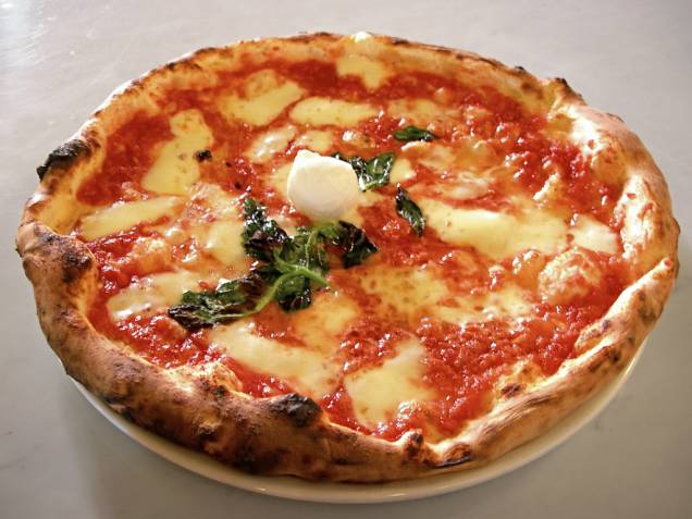 <strong>Pizza, <a href="http://viajeaqui.abril.com.br/paises/italia" rel="Itália" target="_blank">Itália</a></strong><br />  OK, paulistanos dirão que a melhor pizza do mundo é a deles. Os cariocas juram que com ketchup é o ideal. Seja como for, vale a pena conhecer a receita original. Nada daquelas redondas estufadas com massa de pão que os americanos tanto gostam, ou vendidas em pedaços (<em>taglio</em>) encontradas em quiosques por toda a Itália. Estamos falando de uma massa fininha, com cobertura que representam as três cores da bandeira do país: vermelho (molho de tomate), branco (muzzarella de búfala) e verde (manjericão). E, faça a coisa certa, prove essa maravilha em <a href="http://viajeaqui.abril.com.br/cidades/italia-napoles" rel="Nápoles" target="_blank">Nápoles</a>, acompanhada por um bom vinho do sul