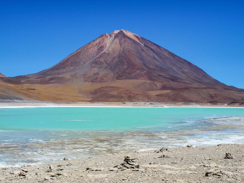 <a href="http://viajeaqui.abril.com.br/paises/bolivia" target="_blank" rel="noopener"><strong>Licancabur, Bolívia</strong></a> Localizado a 40km de <a href="http://viajeaqui.abril.com.br/cidades/chile-san-pedro-de-atacama" target="_blank" rel="noopener">San Pedro de Atacama no Chile</a>, está na fronteira entre os dois países. É ali que está o lago mais alto do mundo, dentro de seu cume de 5.913 metros de altitude. O lago tem apenas 90 x 70 metros e suas águas são mantidas a aproximadamente 6 graus, quentinho para tal altitude, graças a aquecimento geotermal que vem de dentro da terra.