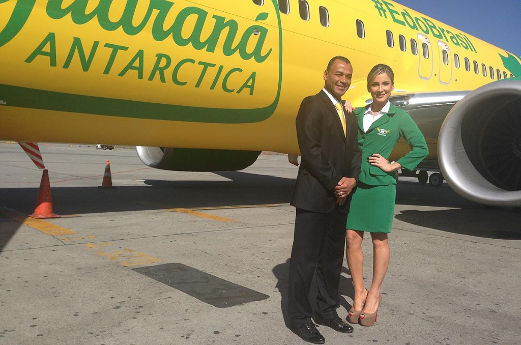 Cafu e Claudia Leitte posam na frente do avião verde e amarelo da Gol