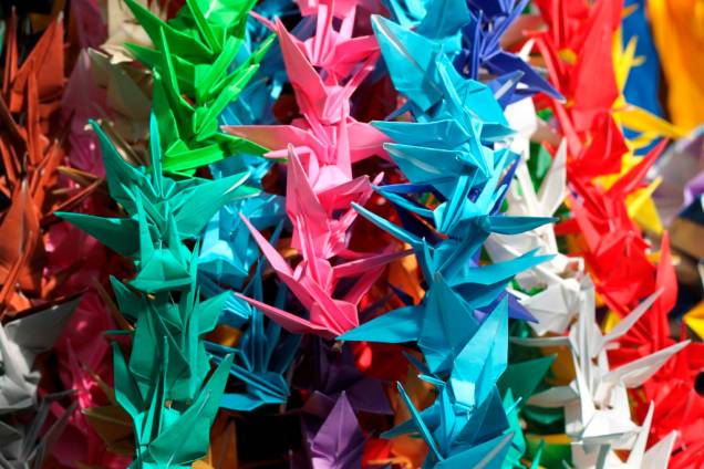 Vítima de leucemia como consequência da radiação da bomba, a pequena Sadako Sasaki acreditava que se recuperaria caso fizesse mil pequenas cegonhas de papel - os <em>origamis </em>de <em>tsuru</em>. Ela viria a morrer ao dobrar 644. Em memória dela e de outras crianças vítimas da guerra, estudantes de todo o Japão enviam para Hiroshima dobraduras de papel. Ora em coloridos feixes de mil, ora com as 356 que faltaram para Sadako Vítima de leucemia como consequência da radiação da bomba, a pequena Sadako Sasaki acreditava que se recuperaria caso fizesse mil pequenas cegonhas de papel - os <em>origamis </em>de <em>tsuru</em>. Ela viria a morrer ao dobrar 644. Em memória dela e de outras crianças vítimas da guerra, estudantes de todo o Japão enviam para Hiroshima dobraduras de papel. Ora em coloridos feixes de mil, ora com as 356 que faltaram para Sadako