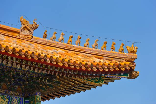 Motivos decorativos em telhado na Cidade Proibida, Pequim, China. Esse tipo de decoração só era realizado em edifícios imperiais, sendo que aqui a procissão de imagens é liderada por um fênix.