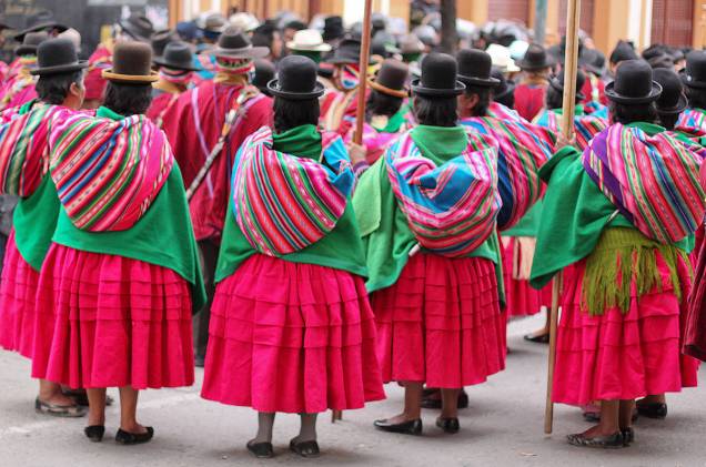 Mulheres indígenas reúnem-se em protesto nas ruas de La Paz, Bolívia. Cada região do país tem o seu povo indígena, e cada povo tem os seus hábitos de vestimenta. Na capital, por exemplo, as mulheres costumam usar saias muito brilhantes e cores vivas e chapéus pretos no topo da cabeça. No interior, o chapéu dá lugar a longas e trabalhadas tranças Mulheres indígenas reúnem-se em protesto nas ruas de La Paz, Bolívia. Cada região do país tem o seu povo indígena, e cada povo tem os seus hábitos de vestimenta. Na capital, por exemplo, as mulheres costumam usar saias muito brilhantes e cores vivas e chapéus pretos no topo da cabeça. No interior, o chapéu dá lugar a longas e trabalhadas tranças