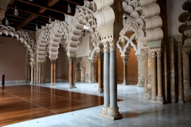 A Aljafería foi construída em um inequívoco estilo mudéjar, com sua características pilastras e arcos. Após sua tomada por Alfonso I, no século 11, o palácio passou a ser a sede do reino de Aragão