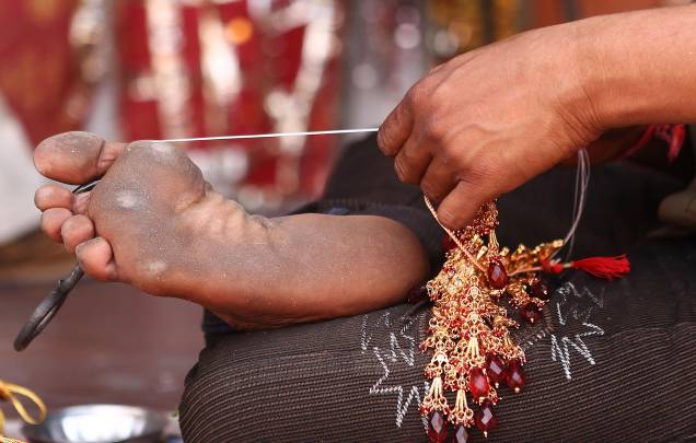 Artesão confecciona bijuteria com uma ajudinha do pé, no centro de Jaipur