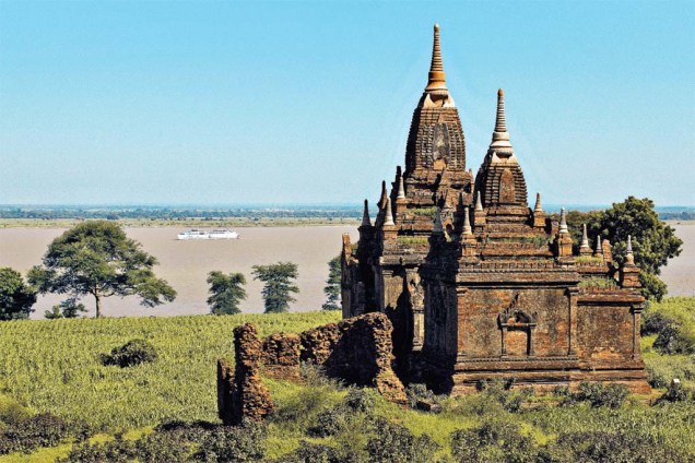 Um dos templos de <a href="https://viajeaqui.abril.com.br/cidades/mianmar-bagan" rel="Bagan" target="_blank">Bagan</a> e o barco The Road to Mandalay, no rio Ayeyarwady, ao fundo