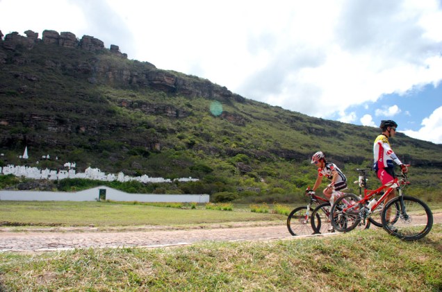 Ciclistas em frente ao Cemitério Bizantino de Mucugê, contruções do século 19 ao pé de um grande paredão