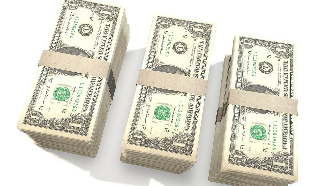 Maços de notas de um dólar em cima de uma mesa branca