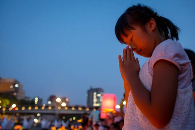 Garota reza em frente ao Domo que marca a história de Hiroshima, cidade japonesa marcada pelo primeiro ataque com bomba atômica no planeta