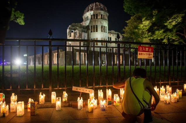 Garota acende velas em frente ao Domo que representa o passado trágico da cidade, quando ela foi destruída pelo primeiro ataque com bomba atômica da história, em 6 de agosto de 1945