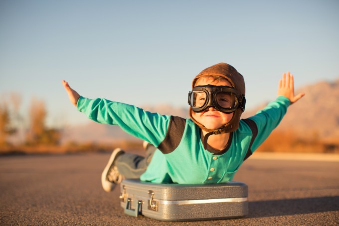 Young Boy with Goggles Imagines Flying on Suitcase