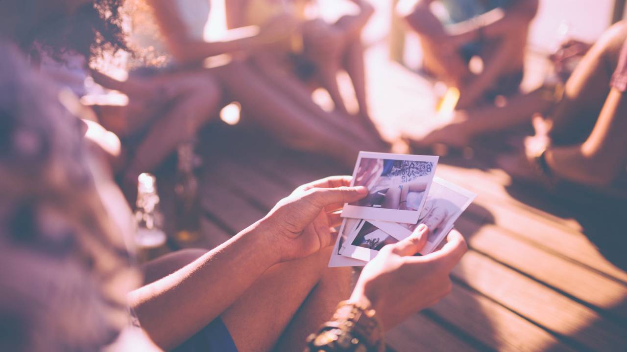 Friends looking at instant photographs of summer fun