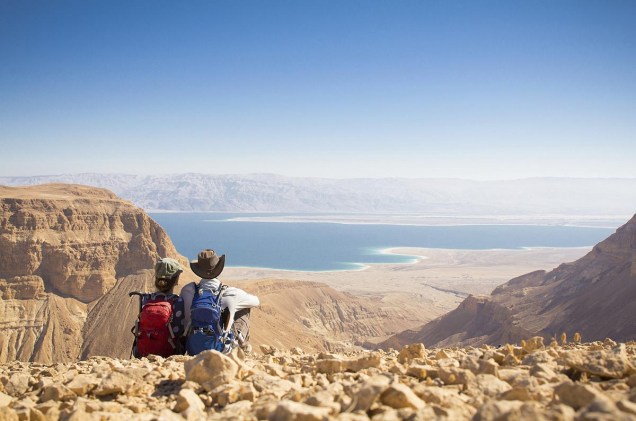 Casal de viajantes observa o Mar Morto do alto de uma colina