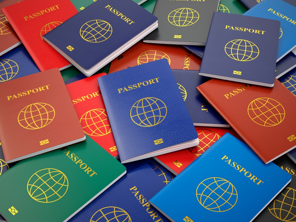 Passaportes de várias cores e países espalhados e amontoados em uma superfície