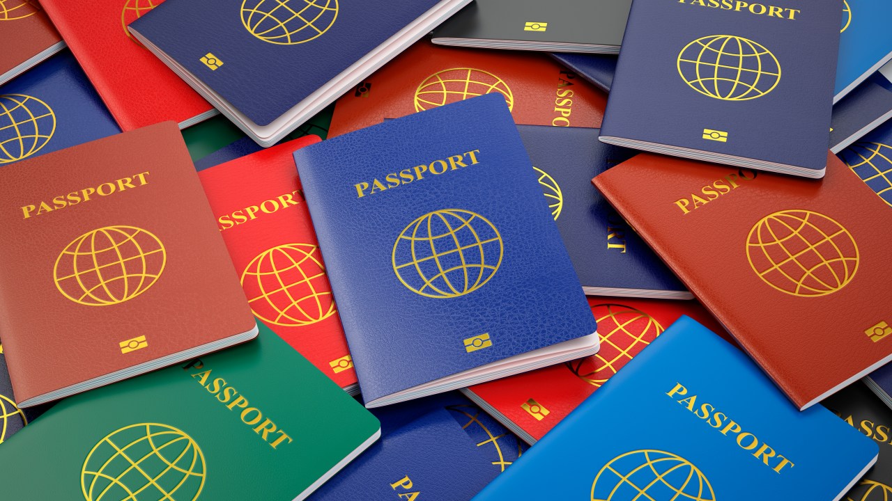 Passaportes de várias cores e países espalhados e amontoados em uma superfície