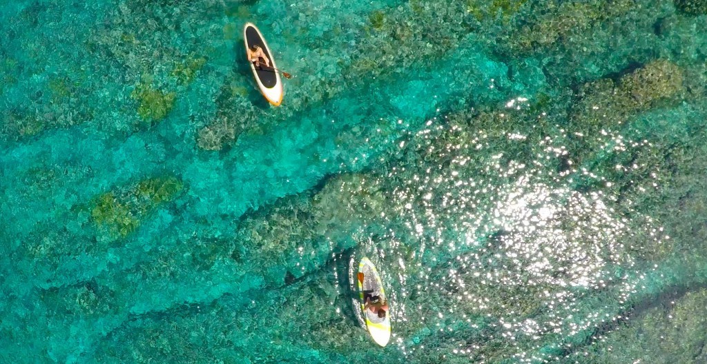 Hóspedes praticam stand up paddle sobre as águas transparentes e os recifes da ilhota na Micronésia (foto: divulgação)