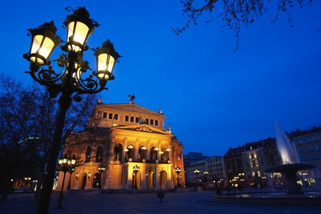 O anoitecer na Alte Oper, também conhecida como Opera House de Frankfurt. A construção, datada de 1880, teve de ser minuciosamente reconstruída após os bombardeios do Holocausto, sendo reinaugurada nos anos 1980