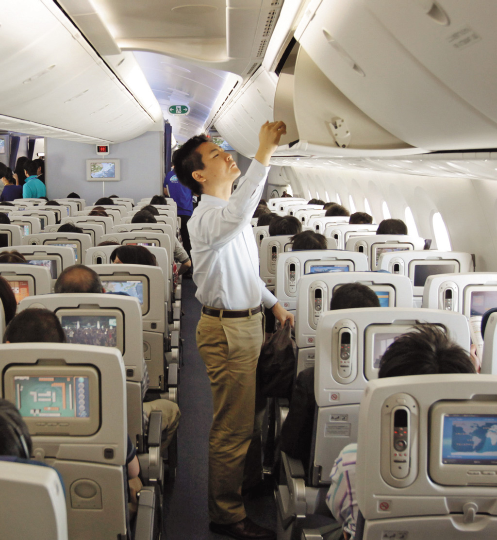 Passageiro acomoda os pertences no bagageiro do Boeing da ANA, em Tóquio