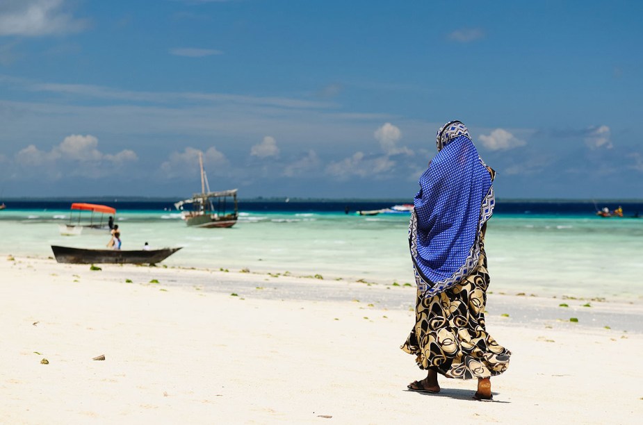 Muçulmana caminha na praia de Zanzibar