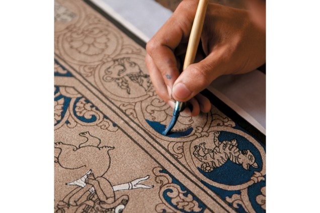 O artesão pinta um calendário birmanês