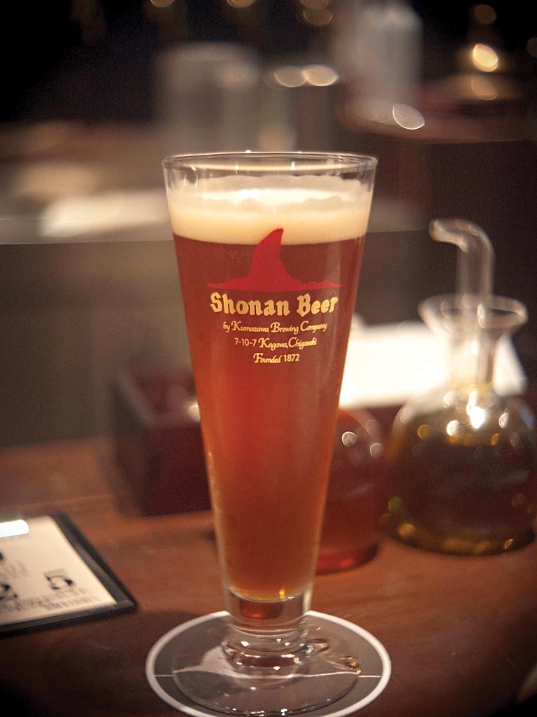Uma taça alta de cerveja japonesa, com fundo de um bar