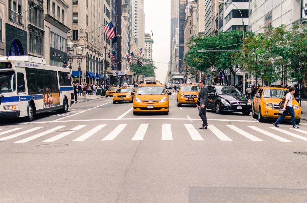 Homem atravessa a rua na faixa de pedestres em avenida de Nova York
