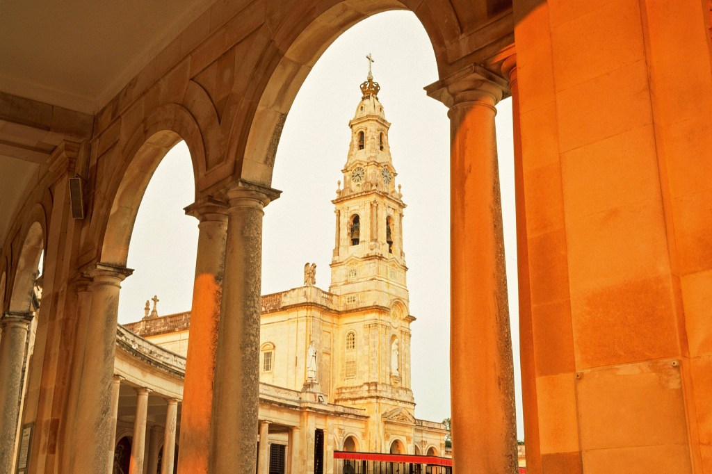 Vista de dentro dos corredores externos da Basílica de Fátima, com a torre do relógio do prédio centralizada