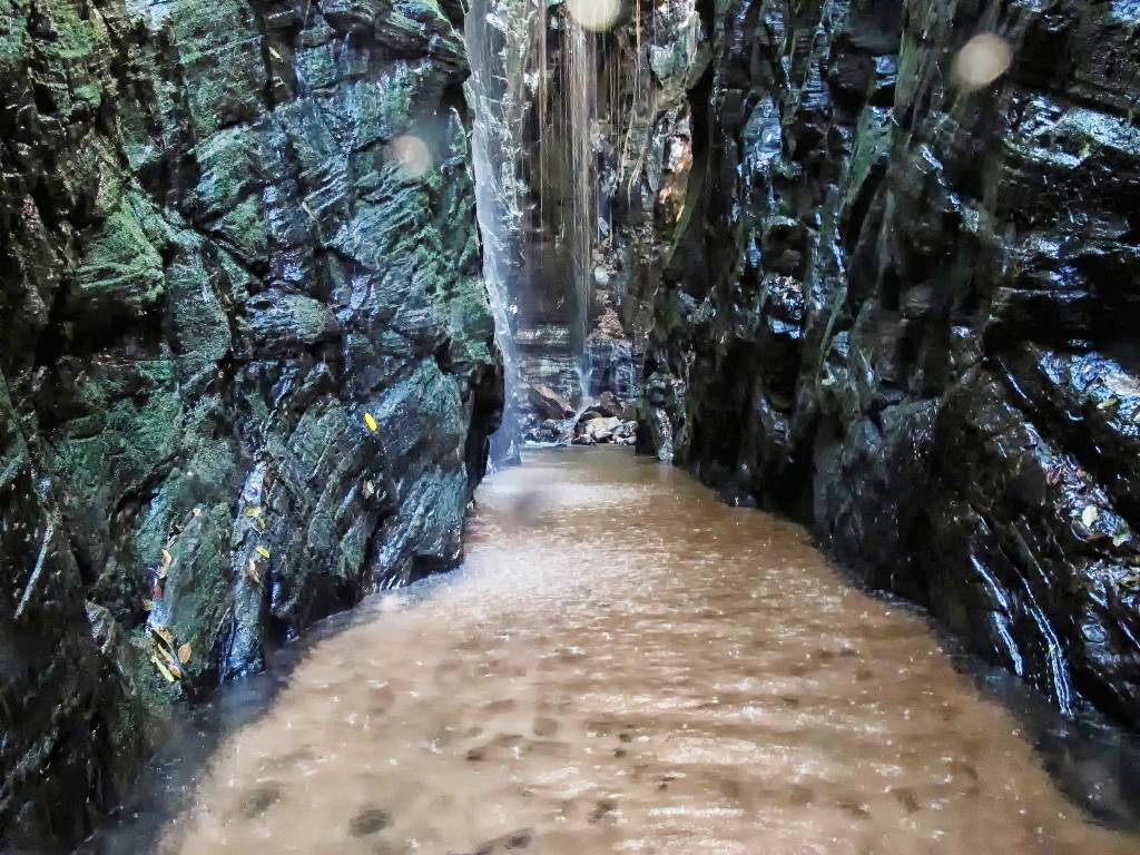 Pedra Caída - cachoeira no meio de um cânion de pedras escuras, com corredor coberto de água até os joelhos, na Chapada das Mesas, Maranhão