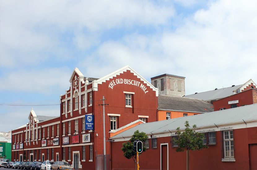 O grande prédio e a frente do restaurante. Na lateral, há, em letras garrafais, o seu nome "The Old Biscuit Mill"