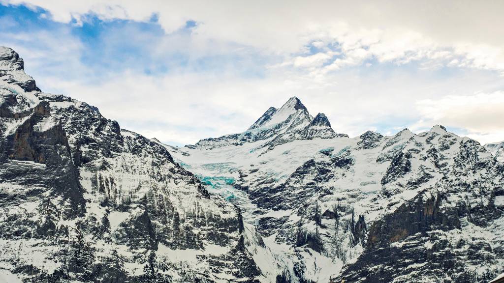 Montanhas enormes e pontiagudas, cobertas de neve e sem vegetação visível