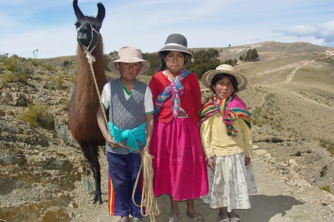 Crianças indígenas bolivianas e lhama na Isla del Sol, no Lago Titicaca, na Bolívia