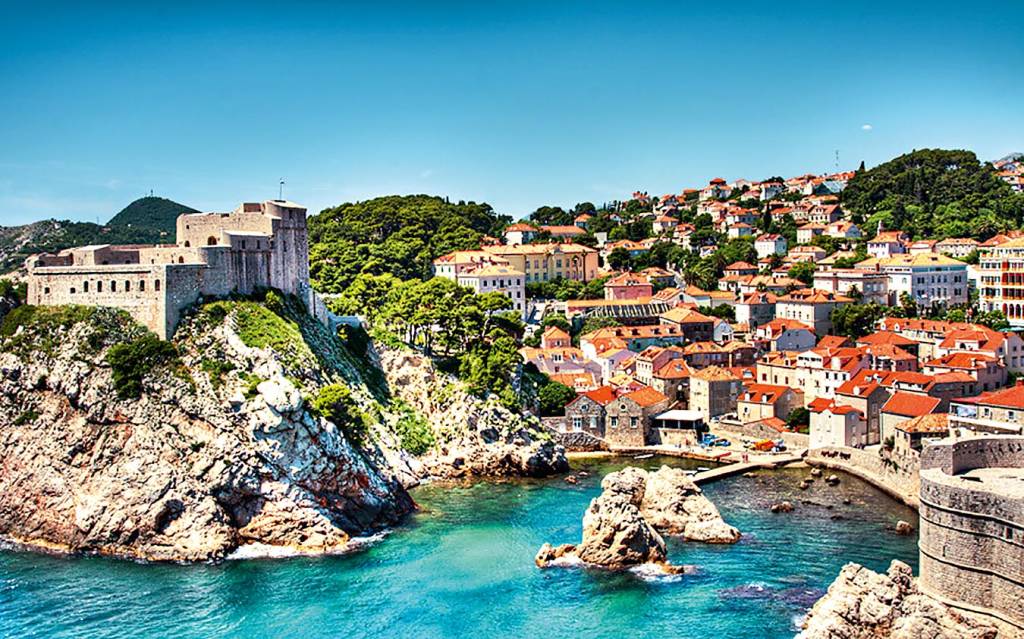 Várias casinhas e um forte preenchem a paisagem íngreme que cerca o porto de Dubrovnik