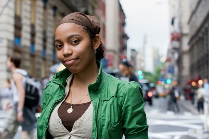 Mulher negra viajante olhando para a câmera em rua de cidade à luz do dia