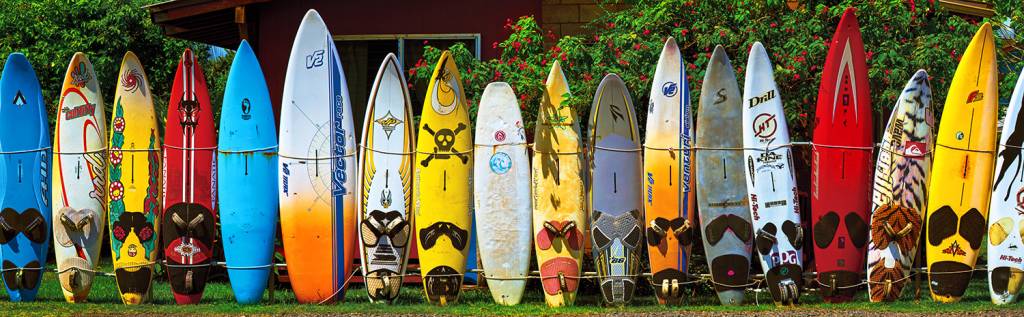 pranchas de surfe de vários tamanhos enfileiradas de pé, unidas por uma corda que envolve toda a fila