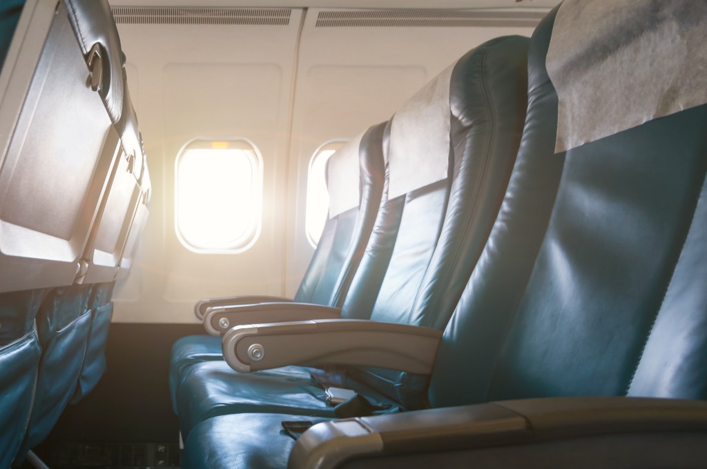 Interior de avião com poltronas de couro vazias e luz do sol entrando pelas janelas