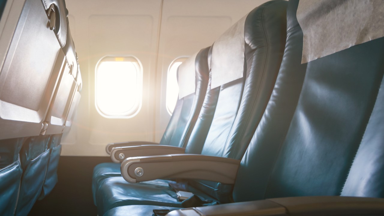 Interior de avião com poltronas de couro vazias e luz do sol entrando pelas janelas