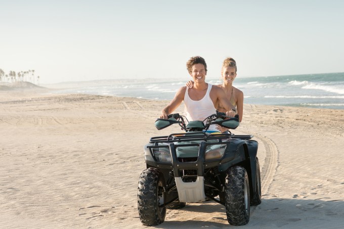 Casal dirigindo um Quad ATV na praia