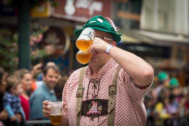 Homem bebendo três copos de cerveja durante o Oktoberfest, em Blumenau.