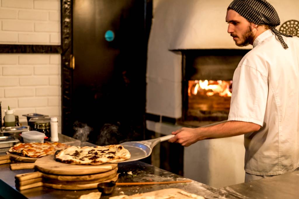 A pizza quentinha e fumegante, recém-saída do forno a lenha: massa fininha e crocante