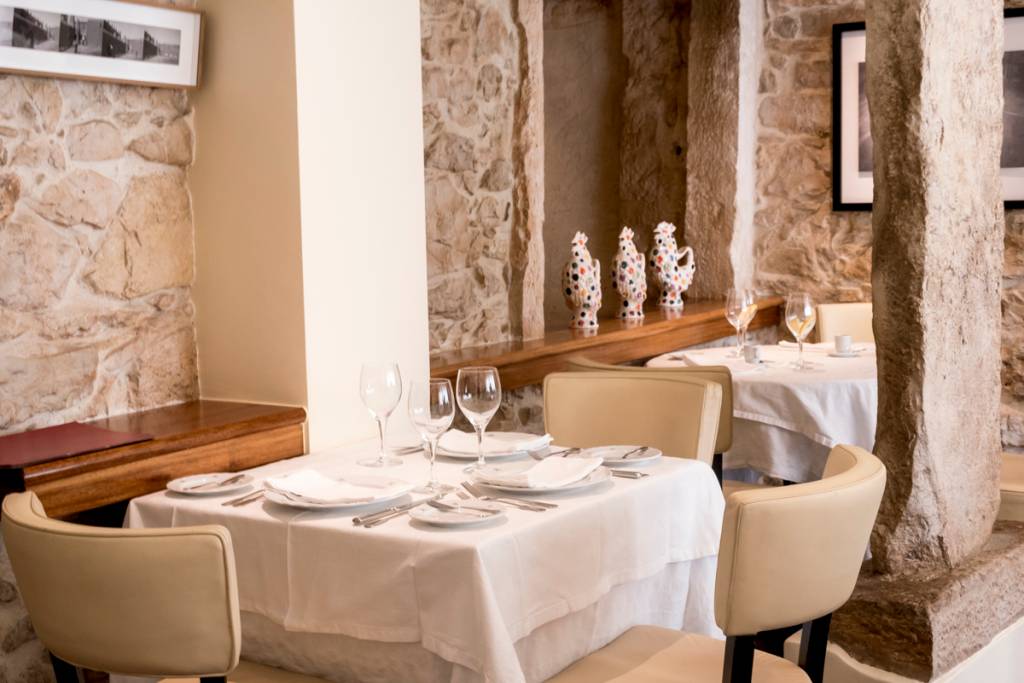 Um cantinho do restaurante: paredes de pedra, toalhas de linho e comida com alma