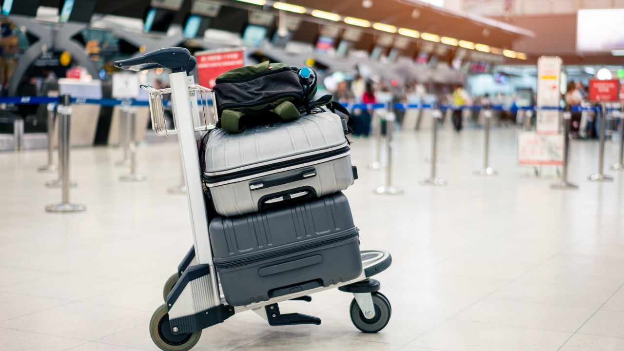 Carrinho com malas em saguão de aeroporto