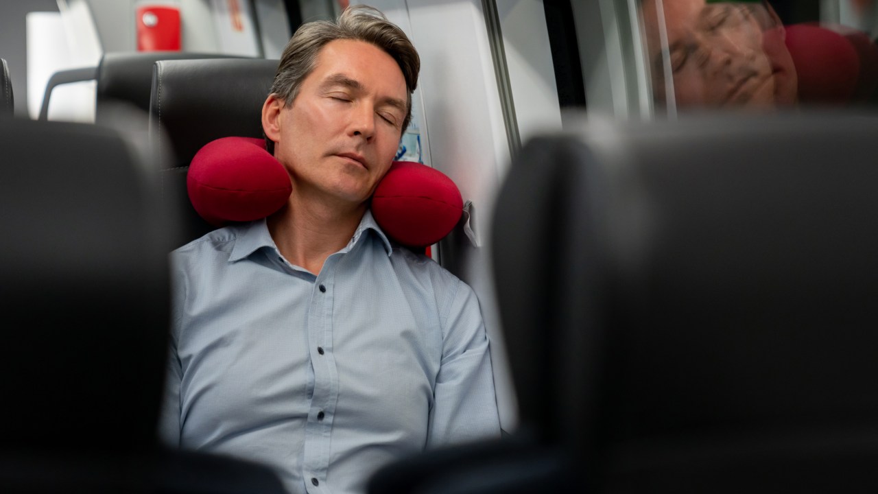 Homem dormindo com almofada de viagem
