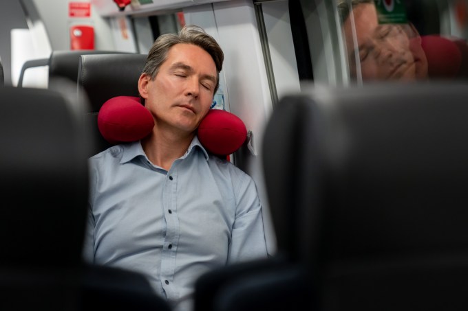 Homem dormindo com almofada de viagem
