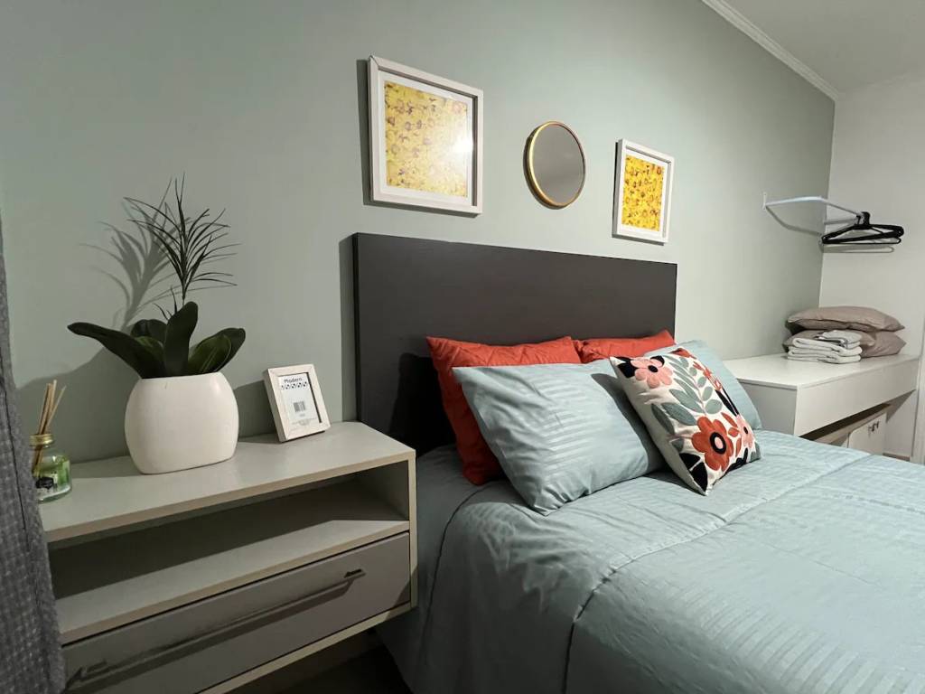 A fotografia colorida mostra um quarto com cama de casal e decoração cinza