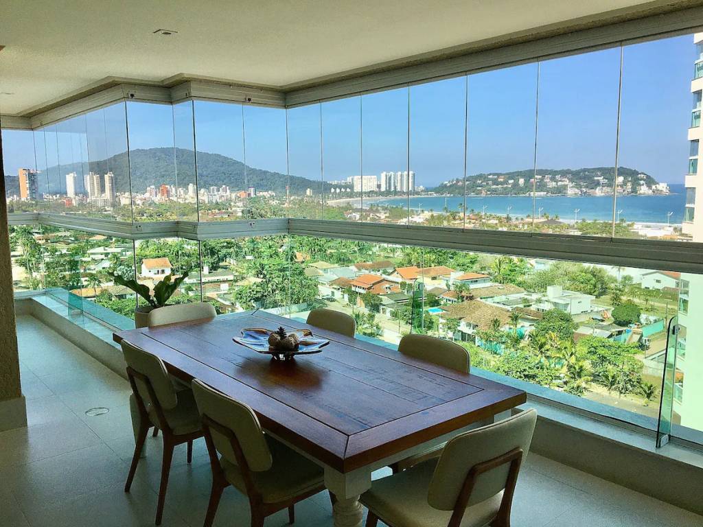 A fotografia mostra uma sala de jantar com uma grande janela com vista para o mar