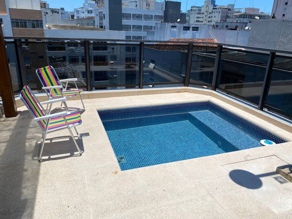 A fotografia mostra uma piscina quadrada em uma varanda com vista para o alto da cidade