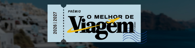 Um bilhete de avião azul claro com o texto PRÊMIO O MELHOR DE Viagem E TURISMO 2026 | 2027, com um avião amarelo sobre a palavra Viagem, sobreposto a uma paisagem de casas brancas em uma montanha e mar azul